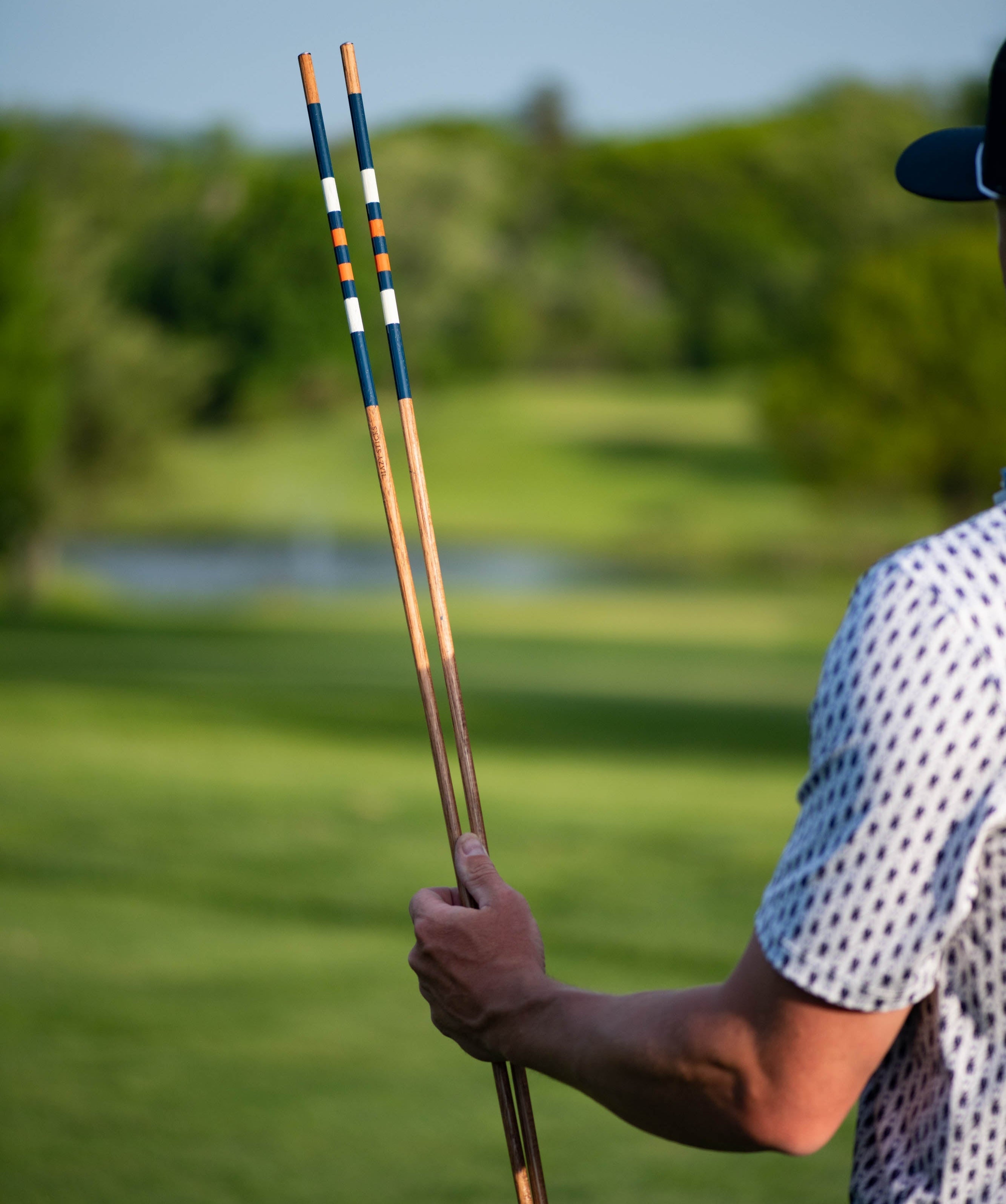 Person holding golf alignment sticks at the golf course