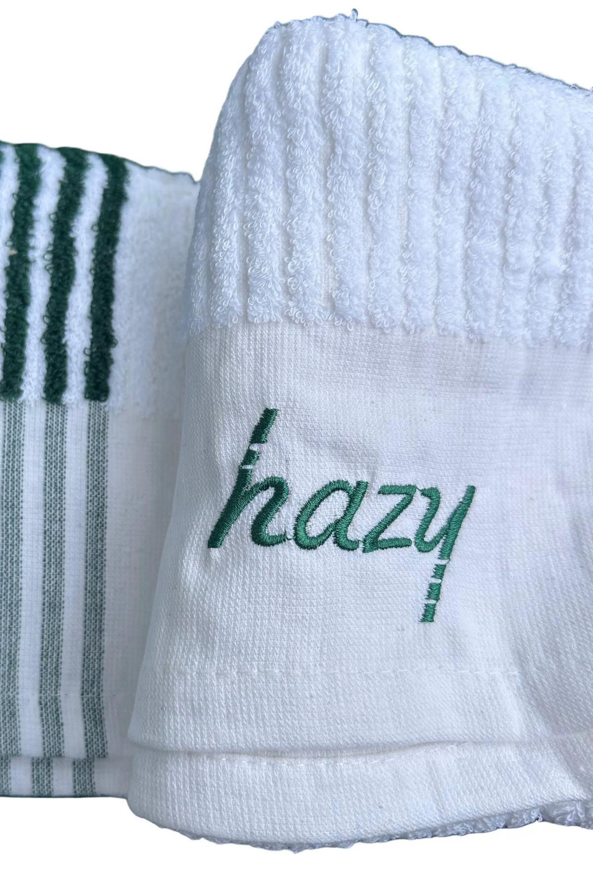 Two white towels with green text and stripes on a grass background