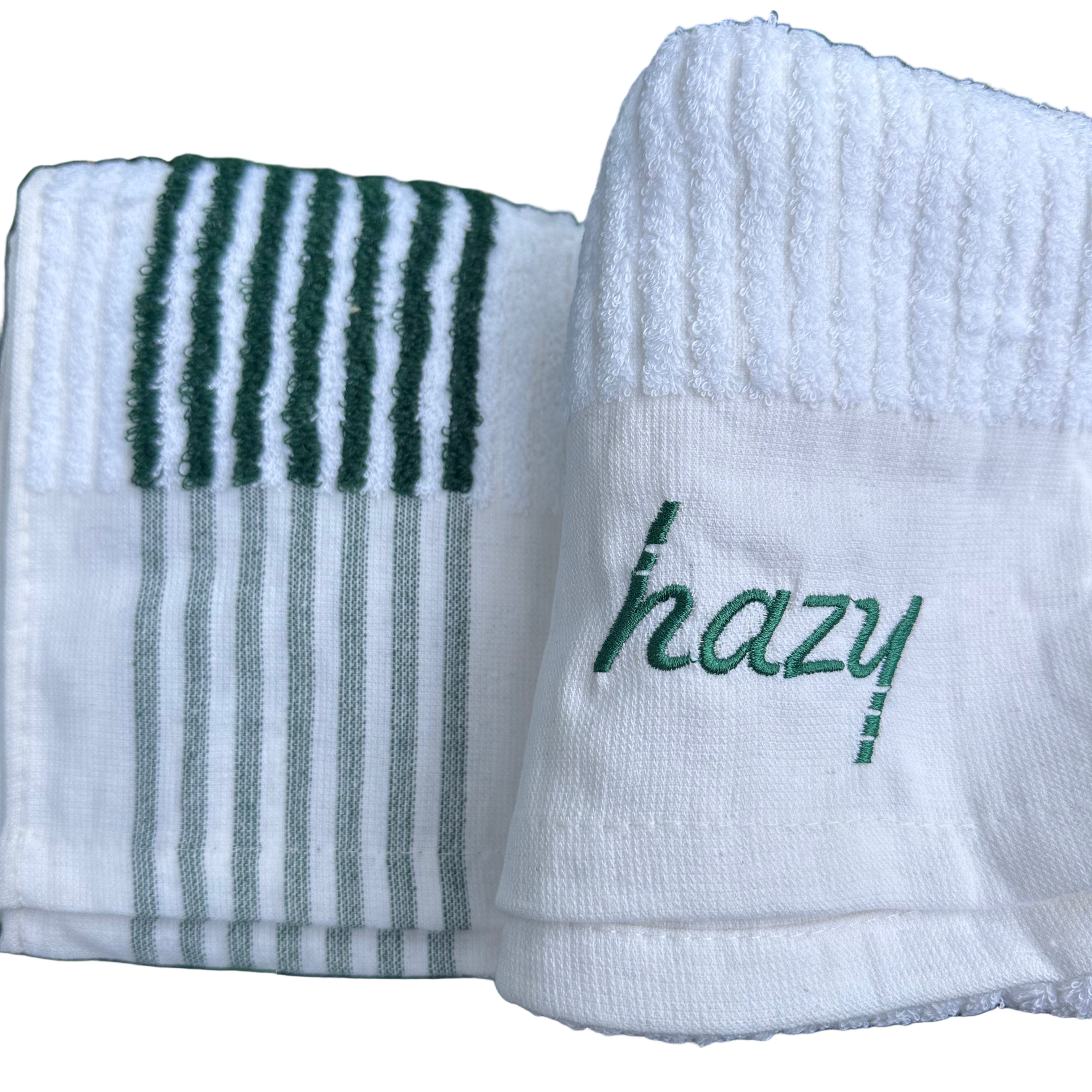 Two white towels with green text and stripes on a grass background