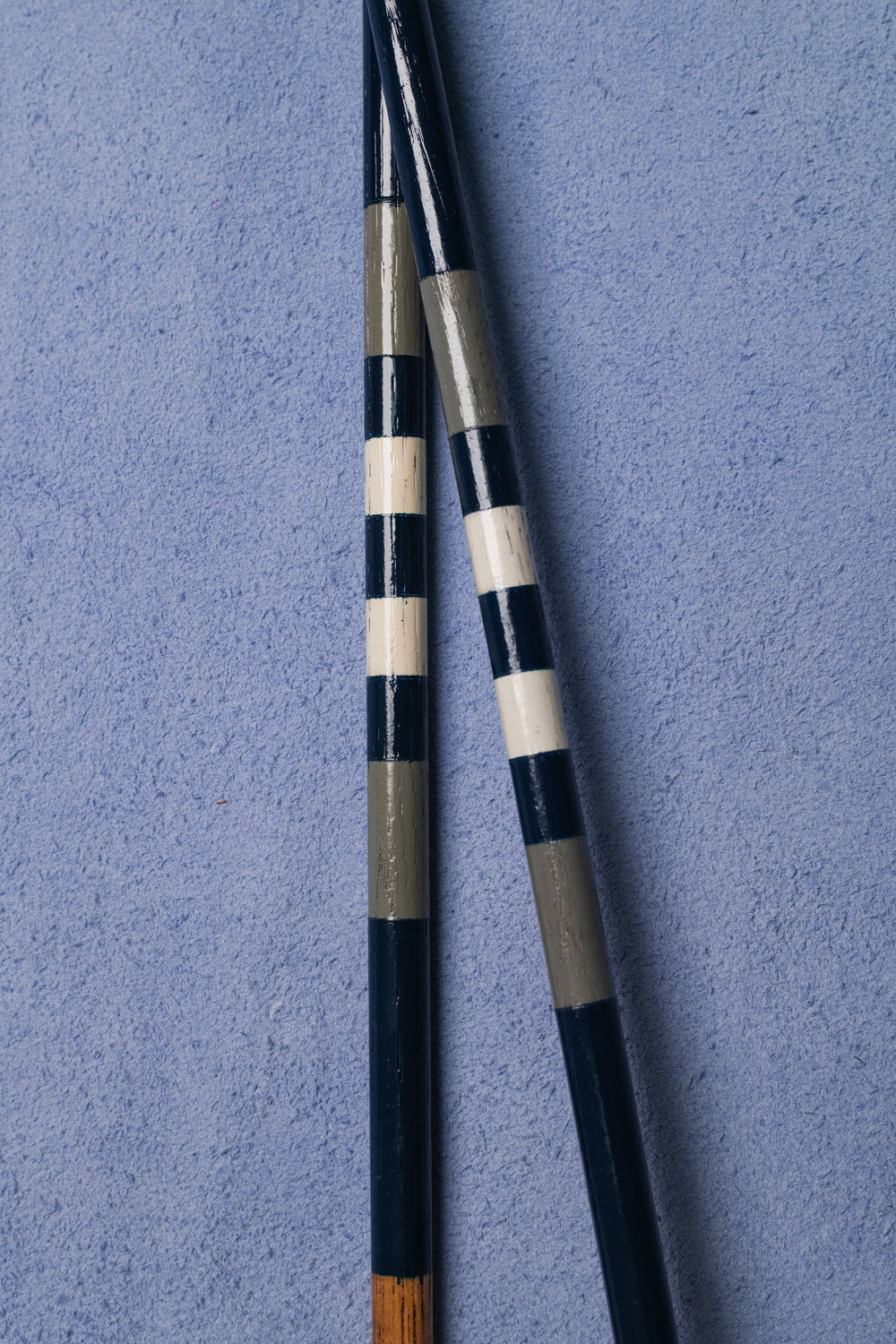 Close-up of hand-painted navy, grey and white hickory alignment sticks.