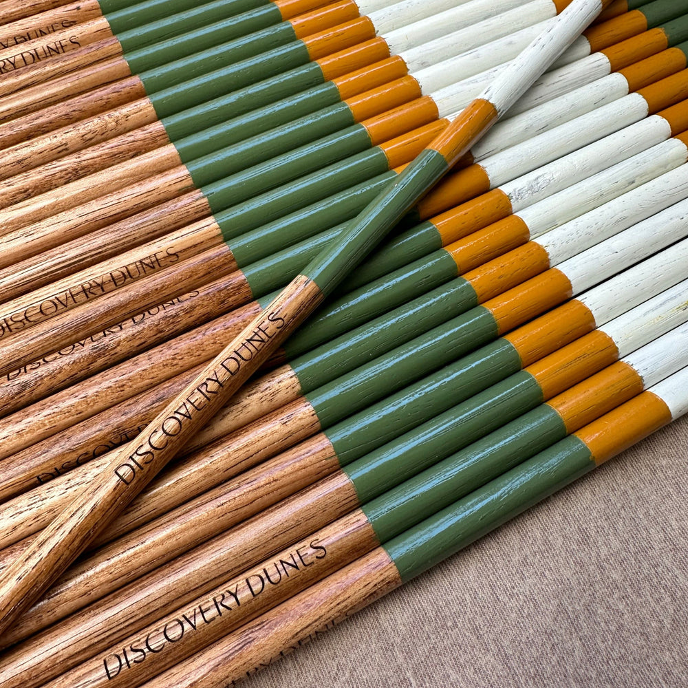 A batch of green, white and gold hickory alignment sticks engraved for Discovery Dunes.